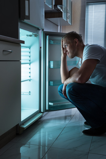 Homme à la recherche de nourriture au réfrigérateur
 - Photo, image