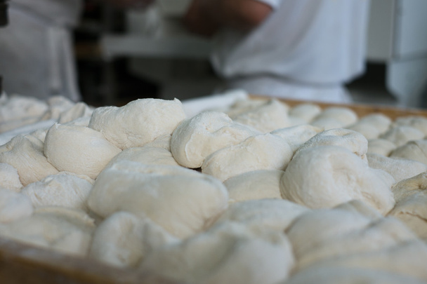 Masa de pan crudo delante de los panaderos
 - Foto, Imagen