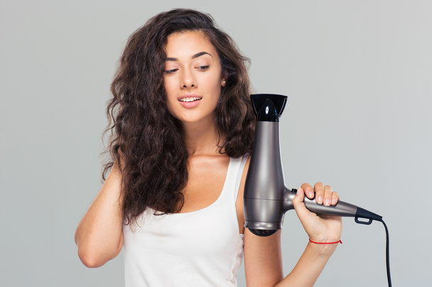 Smiling young woman holding hairdryer - Foto, Bild