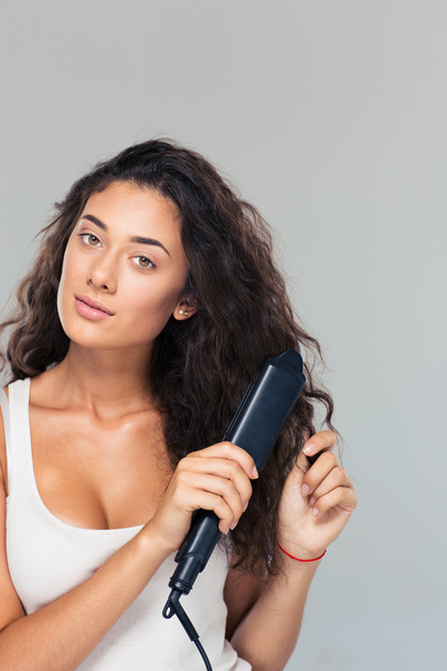 Woman doing hairstyle with hair straightener  - Photo, image