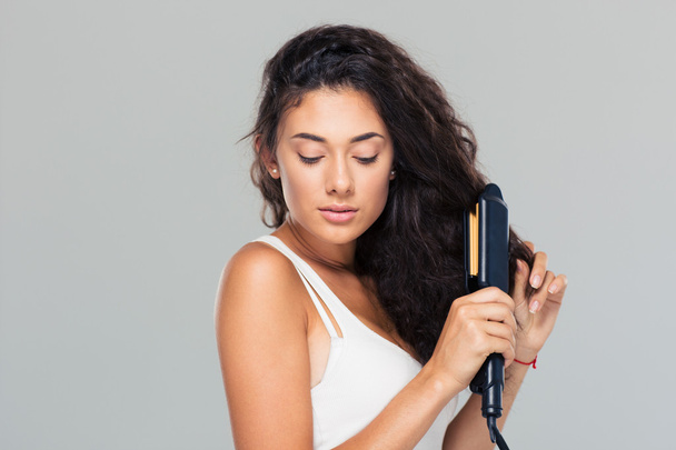 Woman doing hairstyle with hair straightener  - Photo, image