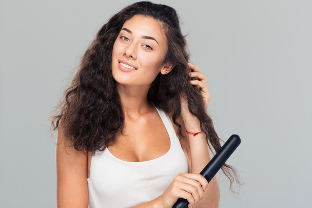 Woman doing hairstyle with hair straightener  - Фото, зображення