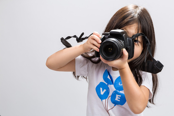 Petite fille appareil photo / Petite fille tenant appareil photo arrière-plan / Petite fille tenant appareil photo reflex numérique pour prendre des photos
 - Photo, image