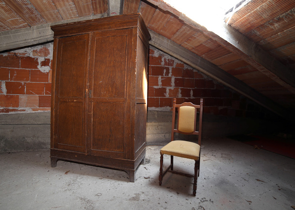 木製のワードローブ、ほこりだらけの屋根裏部屋でアンティークの椅子 - 写真・画像