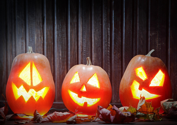 Jack o lanterns Halloween pumpkin face on wooden background - 写真・画像