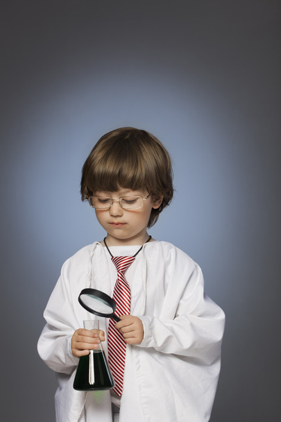 boy studying a substance in a test tube with a magnifying glass - Foto, Imagem