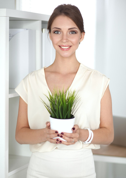 Beautiful woman holding pot with a plant - Фото, зображення
