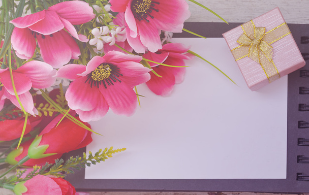 Strauß bunter Blumen und Geschenkbox auf geöffnetem Buch  - Foto, Bild