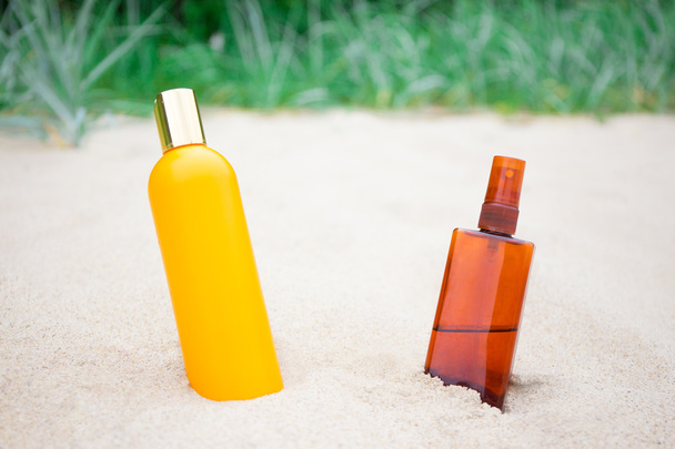suntan lotion and spray bottles on sandy beach - Φωτογραφία, εικόνα
