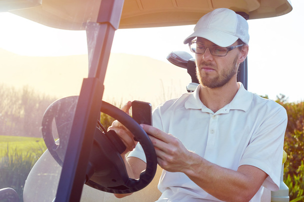 golfer using cellphone app on cart - Fotó, kép