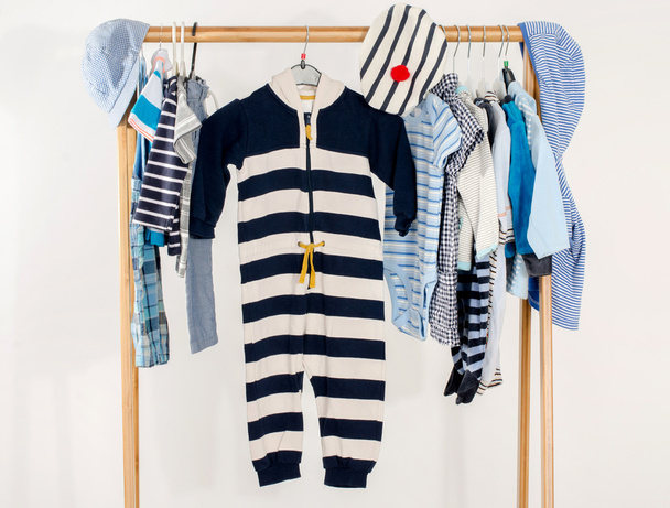Dressing closet with clothes arranged on hangers.Marine wardrobe of newborn,kids, toddlers, babies on a rack.Many t-shirts,pants, shirts,blouses, onesie hanging - Photo, image
