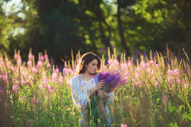 Beautiful young woman, holding lavender in a field on sunset. So - Fotó, kép