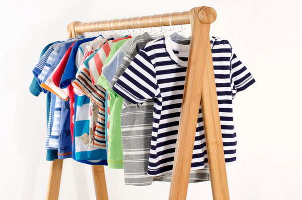 Dressing closet with clothes arranged on hangers.Colorful wardrobe of newborn,kids, toddlers, babies full of all clothes.Many t-shirts,pants, shirts,blouses, onesie hanging - Fotoğraf, Görsel