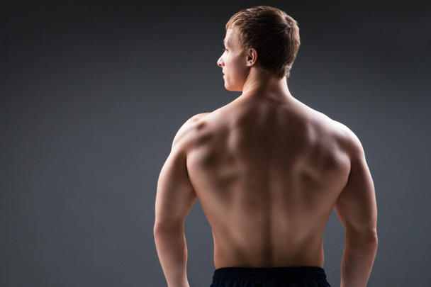 Back view of muscular young man  shows the different movements and body parts - Фото, изображение
