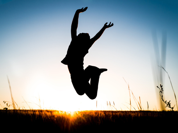 Silhouette du jeune homme heureux qui saute par-dessus la prairie
 - Photo, image