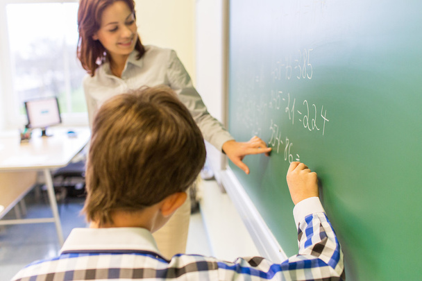 school boy with teacher writing on chalk board - Φωτογραφία, εικόνα