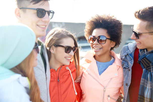 happy teenage friends in shades talking on street - Фото, изображение