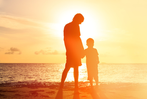siluetit isä ja poika kädestä auringonlaskun aikaan
 - Valokuva, kuva
