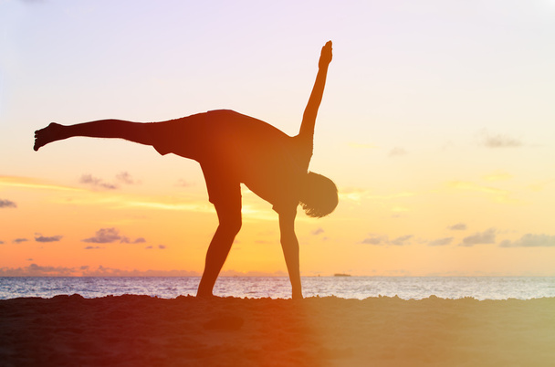 Silhouette of young man doing yoga at sunset - Photo, Image
