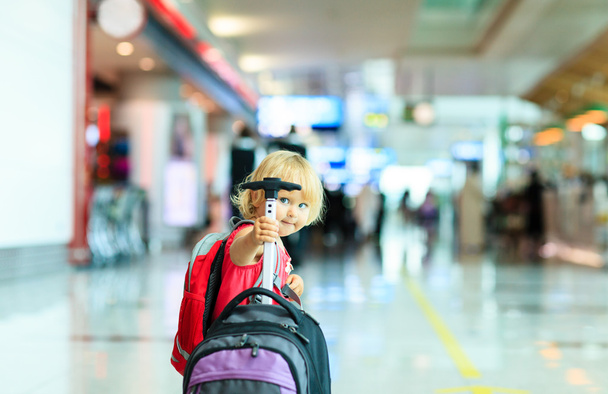 маленькая девочка с чемоданом путешествия в аэропорту
 - Фото, изображение