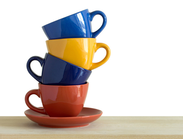 стопка барвистих чашок на столі, ізольована на білому
 - Фото, зображення