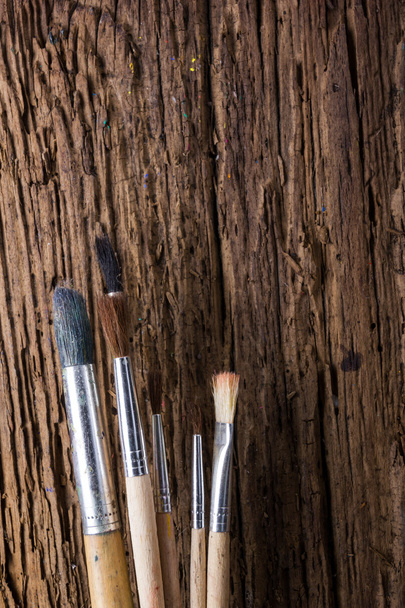 Row of artist paintbrushes on old natural grunge wooden background - Photo, Image