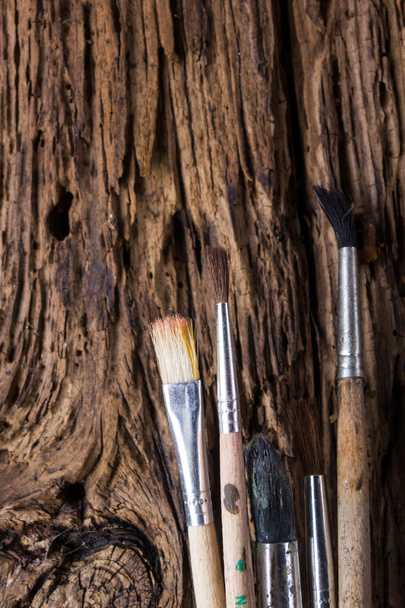 Row of artist paintbrushes on old natural grunge wooden background - Fotó, kép