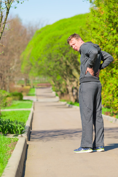 ジョギング中の男性が背中の痛みを始めています。 - 写真・画像