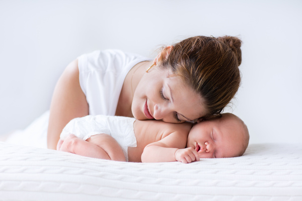 Νεαρή μητέρα και νεογέννητο μωρό σε κατάλευκο υπνοδωμάτιο - Φωτογραφία, εικόνα