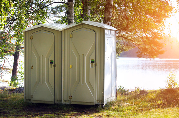 Due servizi igienici portatili o bagno in plastica blu in un parco
 - Foto, immagini