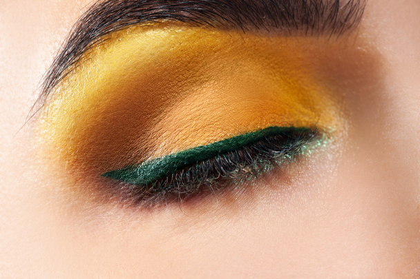 Closed woman eye with yellow makeup and green stripe - Фото, зображення