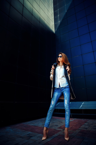 girl in a beige coat and blue jeans - Фото, изображение