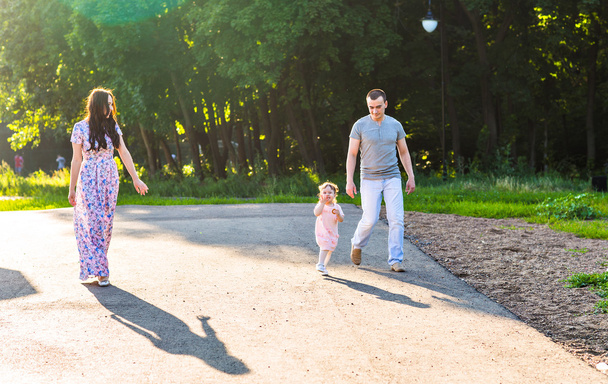 Onnellinen nuori perhe kävelee puistossa. - Valokuva, kuva