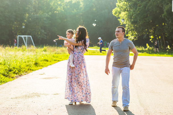 Boldog fiatal család sétál a parkban. - Fotó, kép