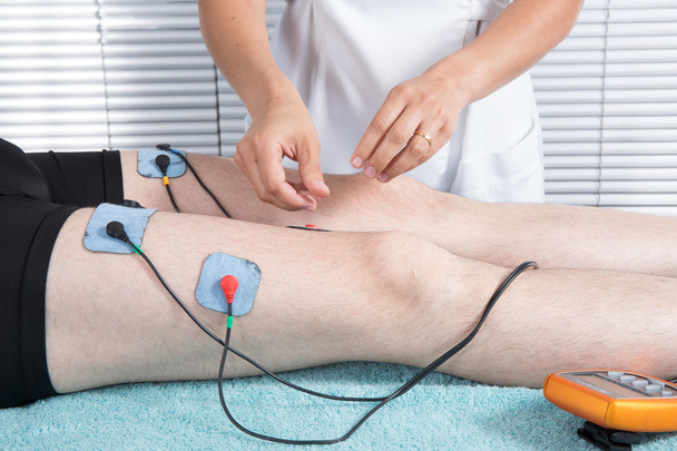 Мужчина получает электрический массаж для мышц ног в спа
 - Фото, изображение