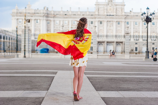 Young woman in front of Palacio de Oriente - the Royal Palace of Madrid, holding a flag. - Fotoğraf, Görsel