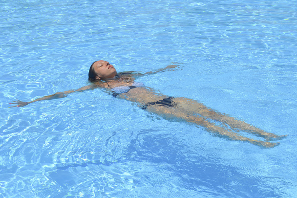 Девушка плавает в воде в бассейне. Летний отдых
 - Фото, изображение