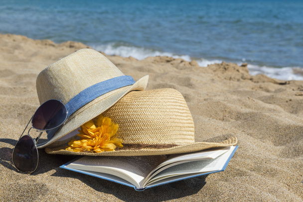 Солом'яні капелюхи, сонцезахисні окуляри та книга на пляжі. Літні канікули
  - Фото, зображення