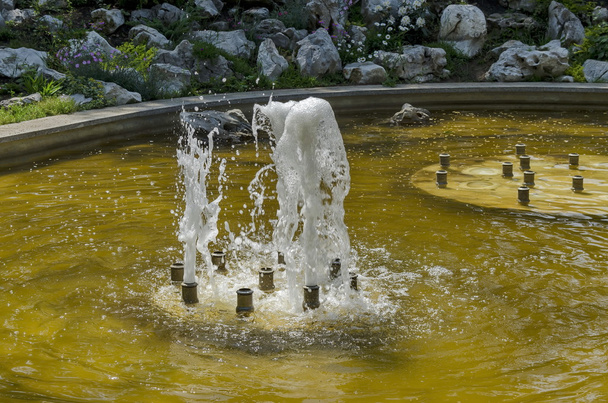 Grupo de pequenas fontes de água que fluem na frente beleza rockery
 - Foto, Imagem