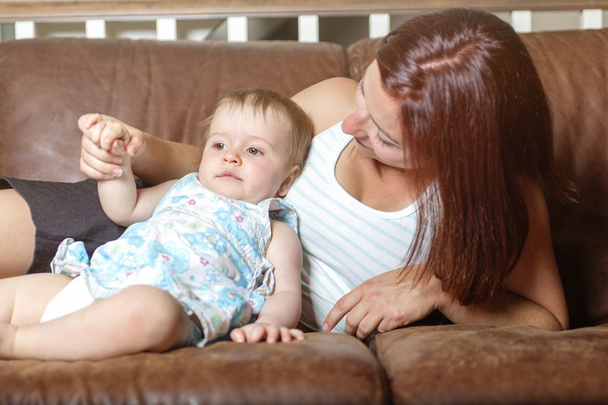 Boldog, szép fiatal anya és a baba, megállapításáról szóló, a kanapén - Fotó, kép