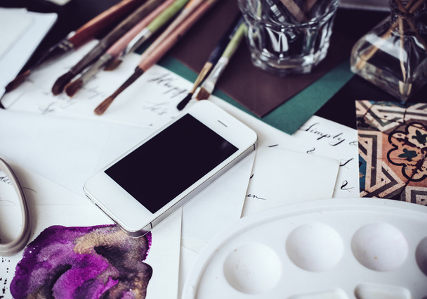Smartphone on a table in the artist studio - Foto, Bild