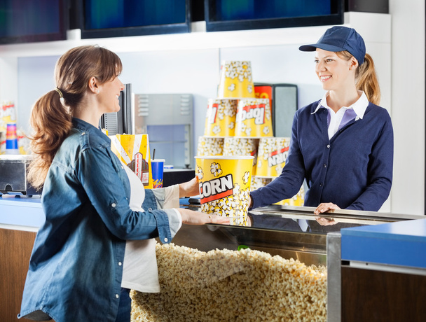 Беременная женщина покупает попкорн в кинематографе
 - Фото, изображение