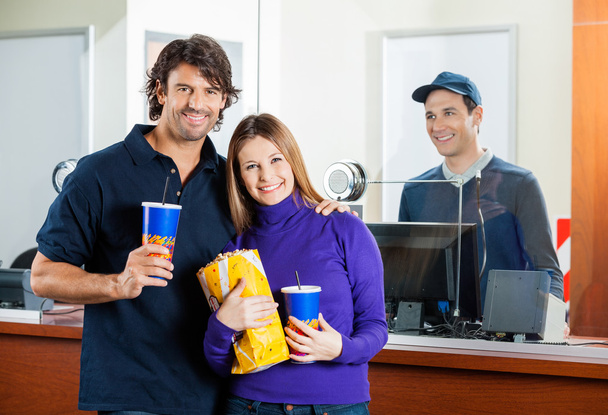 Happy Couple Holding Snacks with Seller at Box Office Counter
 - Фото, изображение