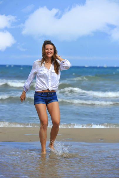 young beautiful girl walking on water at sea shore smiling happy - Foto, immagini