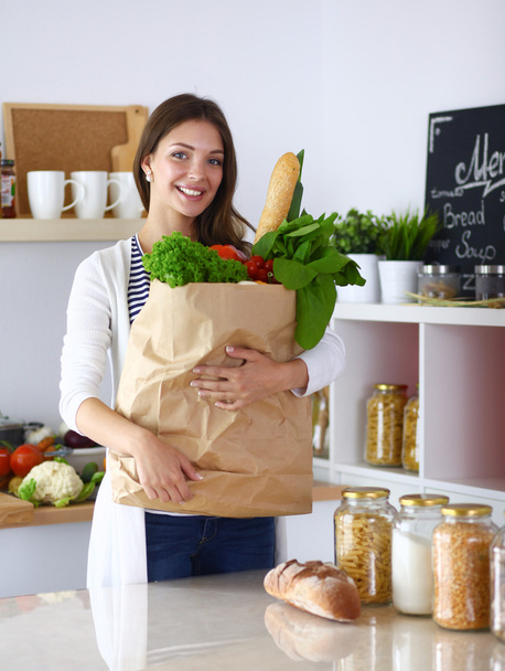 Молода жінка тримає продуктовий сумку з овочами
  - Фото, зображення