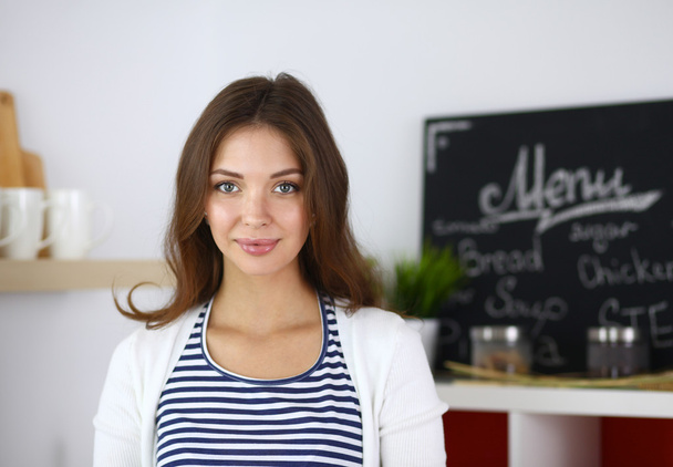 Young woman standing in kitchen at home - Foto, immagini