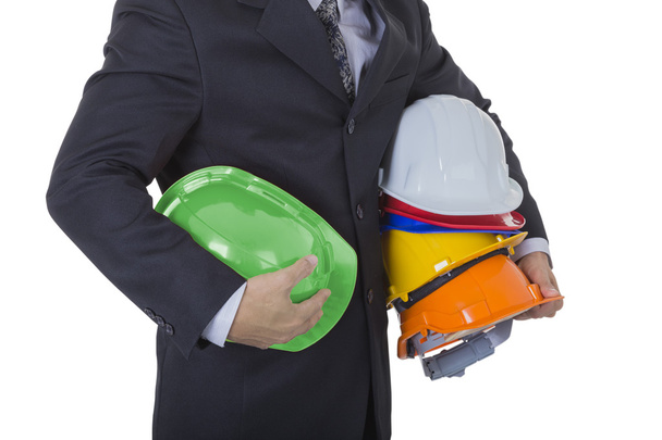 Бізнесмен тримає шолом безпеки шість кольорів для роботи на руці
 - Фото, зображення