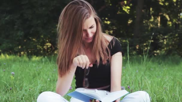 Feliz chica hermosa leyendo un libro en el parque
 . - Metraje, vídeo