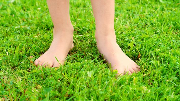 緑の芝生の上の少女の足 - 写真・画像