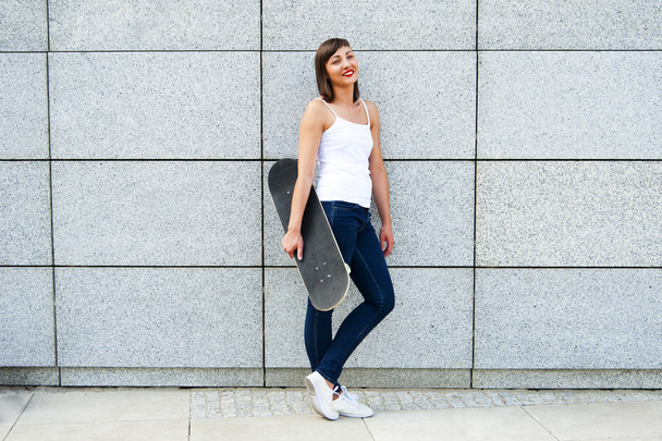Mladá dívka s skateboard v městě zdi usmíváš. - Fotografie, Obrázek